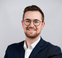 Porträtfoto eines Teammitglieds der Reisewelt Fröhlich mit Brille und Anzug.